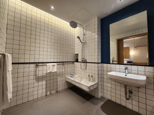a white tiled bathroom with a sink and a mirror at Kram Pattaya in Pattaya North