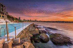 a view of a beach at sunset with the ocean at Spirit of Bondi Apartments in Sydney