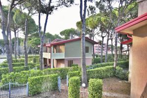 une maison dans un parc planté d'arbres et de buissons dans l'établissement Villa Cellini, à Lignano Sabbiadoro