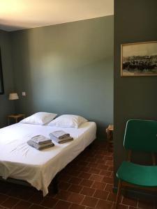 a bedroom with a bed and a green chair at Villa neuve et moderne avec piscine à Grimaud in Grimaud