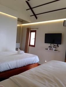 a bedroom with two beds and a flat screen tv at CHEENI HILL RESORTS in Kanthalloor