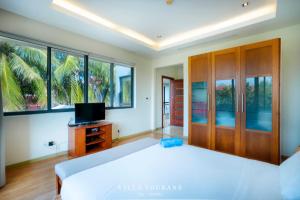 um quarto com uma cama, uma televisão e janelas em Villa Tourane em Da Nang
