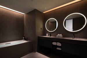 a bathroom with two sinks and a tub and two mirrors at Sunstone Plaza Hotel in Binzhou