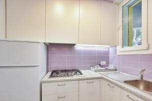 cocina con fogones, fregadero y azulejos púrpura en Villa Cristina, en Lignano Sabbiadoro