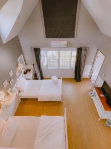 um quarto amplo com 2 camas e uma janela grande em Baan JaoKorKluay บ้านเจ้ากอกล้วย em Chiang Rai