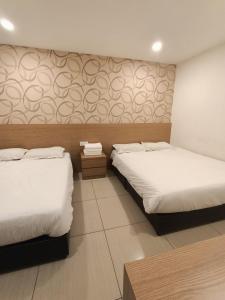 マラッカにあるDYAYA Hotelのベッド2台が備わる壁の客室で、