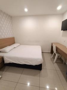 - une petite chambre avec un lit et un bureau dans l'établissement DYAYA Hotel, à Malacca