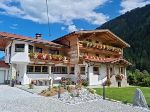 a house in the mountains with flowers on the balcony at Landhaus Hofer in Neustift im Stubaital