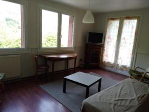 ein Wohnzimmer mit einem Tisch, Fenstern und einem Bett in der Unterkunft Le Veymont in Saint-Martin-en-Vercors