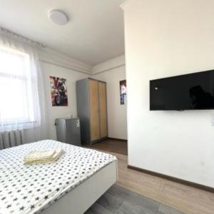 a bedroom with a bed and a flat screen tv at ABS Guest House Osh in Osh
