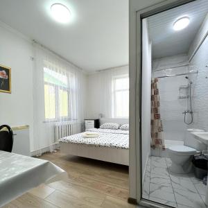 a white bathroom with a bed and a shower at ABS Guest House Osh in Osh