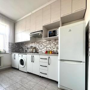 a kitchen with white cabinets and a washer and dryer at ABS Guest House Osh in Osh