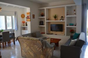 un soggiorno con divani, tavolo e TV di Moumouri's House a Gastouri
