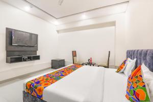 FabHotel Silver Stone Inn في لاكناو: غرفة نوم مع سرير وتلفزيون على الحائط
