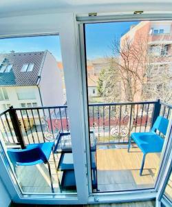 balcón con 2 sillas, mesa y puerta de cristal en Lemon Premium Apartment, en Szeged