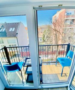a balcony with two chairs and a table and a glass door at Lemon Premium Apartment in Szeged