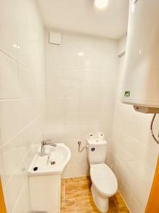 a white bathroom with a toilet and a sink at Lemon Premium Apartment in Szeged