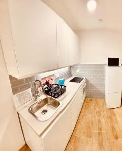 a white kitchen with a sink and a stove at Lemon Premium Apartment in Szeged +2 photos