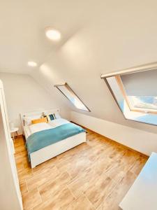 a white bedroom with a bed and two windows at Lemon Premium Apartment in Szeged