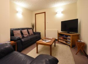 sala de estar con sofá de cuero negro y TV de pantalla plana en Balcarres Bed and Breakfast en Fort William