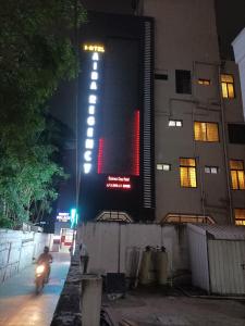 a person riding a motorcycle in front of a building at night at Hotel Aiba Regency in Coimbatore