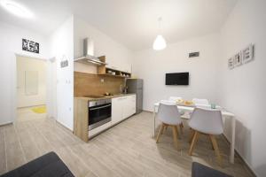een keuken met een tafel en 2 witte stoelen bij Apartments Miku in Pridraga