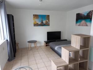 1 dormitorio con 1 cama, TV y mesa en Studio Lumineux Saint-Étienne Bellevue, en Saint Etienne