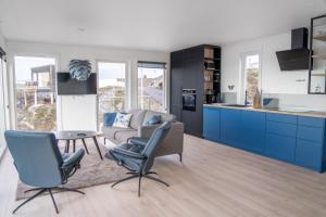uma cozinha com armários azuis, um sofá e uma mesa em Runde Panorama - Trollvogga em Runde