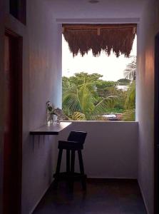 a window with a table and a stool in a room at Hostel Humanity in Puerto Morelos