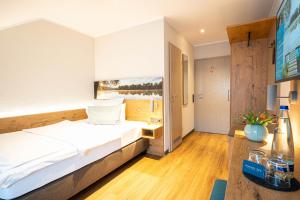 ein Hotelzimmer mit einem Bett und einem TV in der Unterkunft Sopherl am See in Weßling