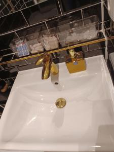 a white sink with gold fixtures on a shelf at CITYLIFE Apartments Economy Osnabrück in Osnabrück