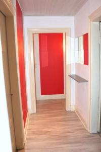 un couloir vide avec un mur rouge dans une chambre dans l'établissement Le Cocon - 3 pièces Mulhouse Gare/Centre, à Mulhouse