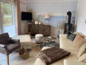 ein Wohnzimmer mit einem Sofa, Stühlen und einem TV in der Unterkunft Villa Gudrun, luxury Beach House in Zingst