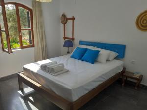 a large bed with blue pillows and towels on it at Porto Heli Apartments in Palekastron