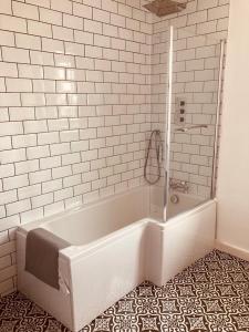 baño blanco con bañera y suelo de baldosa. en Flat 6 George Street, en Teignmouth