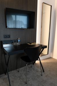 - un bureau noir avec une chaise et un miroir dans l'établissement Hotel Apostroff, à Coxyde