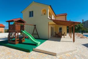 a house with a playground with a slide at Villa Valentina Nin in Ninski Stanovi