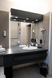 ein Badezimmer mit einem Waschbecken und einem großen Spiegel in der Unterkunft Hotel Apostroff in Koksijde