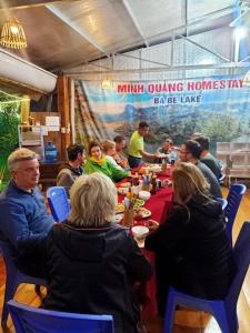 een groep mensen die aan een lange tafel zitten bij Minh Quang homestay in Ba Be18