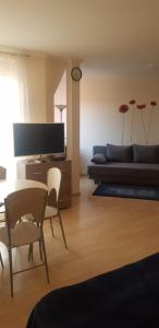 uma sala de estar com um sofá, uma mesa e cadeiras em Boglárka Apartman em Hajdúszoboszló