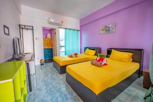 a bedroom with two beds with yellow and purple walls at Noble Thippanate in Chiang Mai
