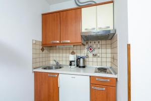 een kleine keuken met houten kasten en een wastafel bij Apartments with a parking space Medulin - 7495 in Medulin