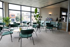 a waiting room with chairs and tables and windows at Hotel Apostroff in Koksijde