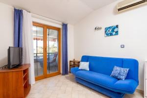 niebieską kanapę w salonie z telewizorem w obiekcie Apartment Medulin 7495b w Medulinie