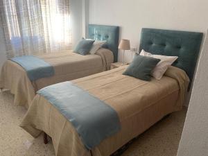 - une chambre avec 2 lits avec des têtes de lit bleues dans l'établissement Apartamento Los Pinares, à Chipiona