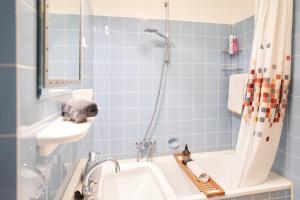 W wyłożonej niebieskimi kafelkami łazience znajduje się umywalka i wanna. w obiekcie Gemütliches und helles Studio Apartment mit Balkon, Badewanne, WLAN, Parkplatz w Bremie