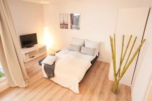 Dieses weiße Zimmer verfügt über ein Bett und einen TV. in der Unterkunft Gemütliches und helles Studio Apartment mit Balkon, Badewanne, WLAN, Parkplatz in Bremen