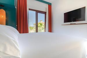 a bedroom with a bed and a tv and a window at 777 Alaçatı Adults only in Alacati