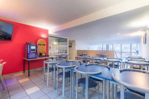 un restaurant avec des tables et des chaises et un mur rouge dans l'établissement Appart'City Classic Lyon Part Dieu Villette, à Lyon