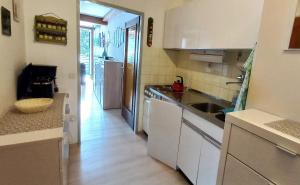 a kitchen with white cabinets and a sink and a hallway at DANIELA Seeblick Appartement Haus Hänsel Gretel am Ossiacher See, Hallenbad, Skiarena Gerlitzen in Stiegl